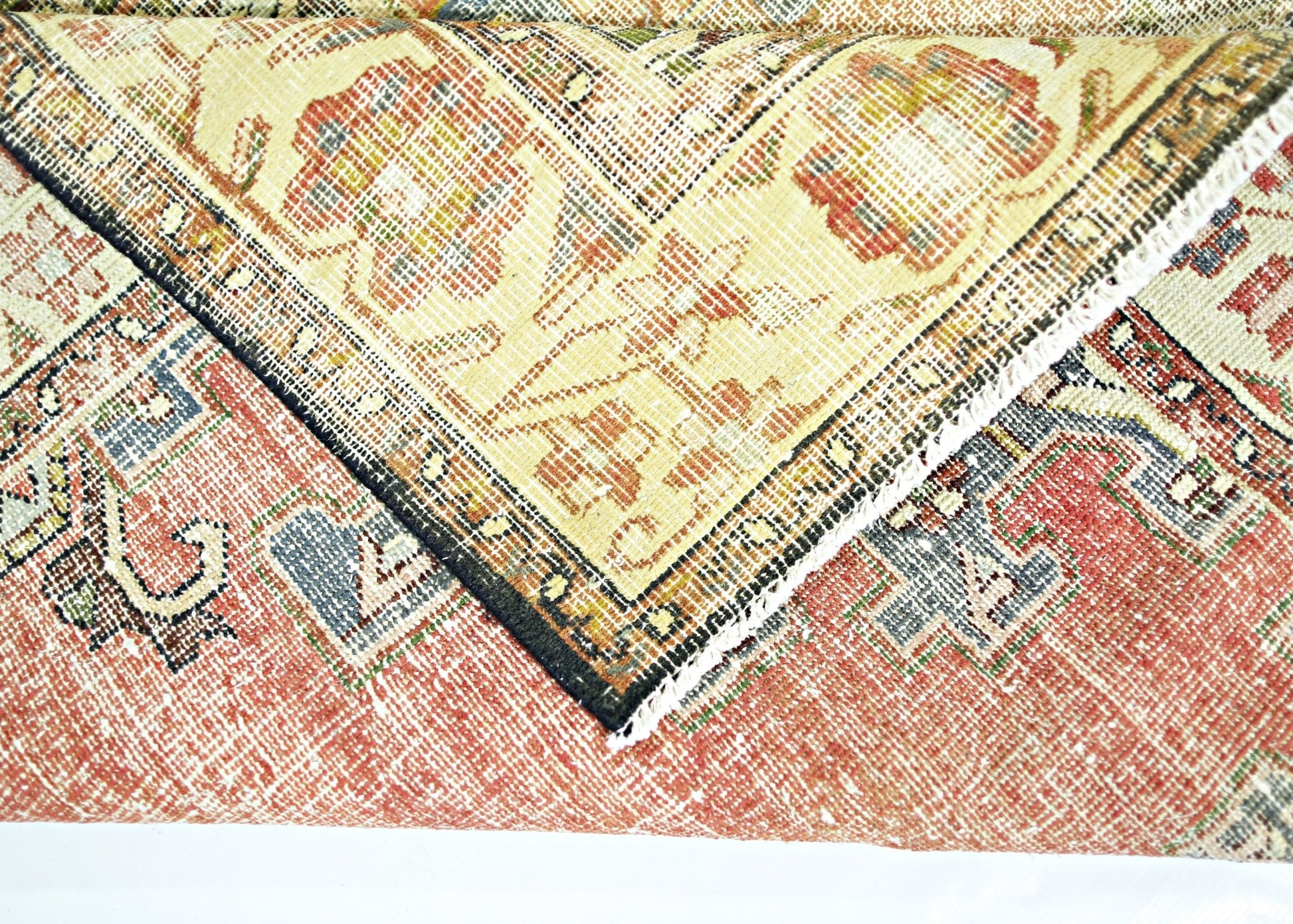 A folded vintage Persian rug featuring a traditional floral pattern in red, blue, and cream tones.