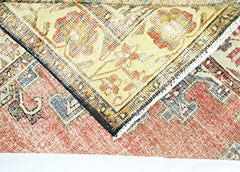 A folded vintage Persian rug featuring a traditional floral pattern in red, blue, and cream tones.