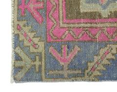 A corner detail of a vintage Persian Hamadan rug featuring geometric patterns in pink and blue.