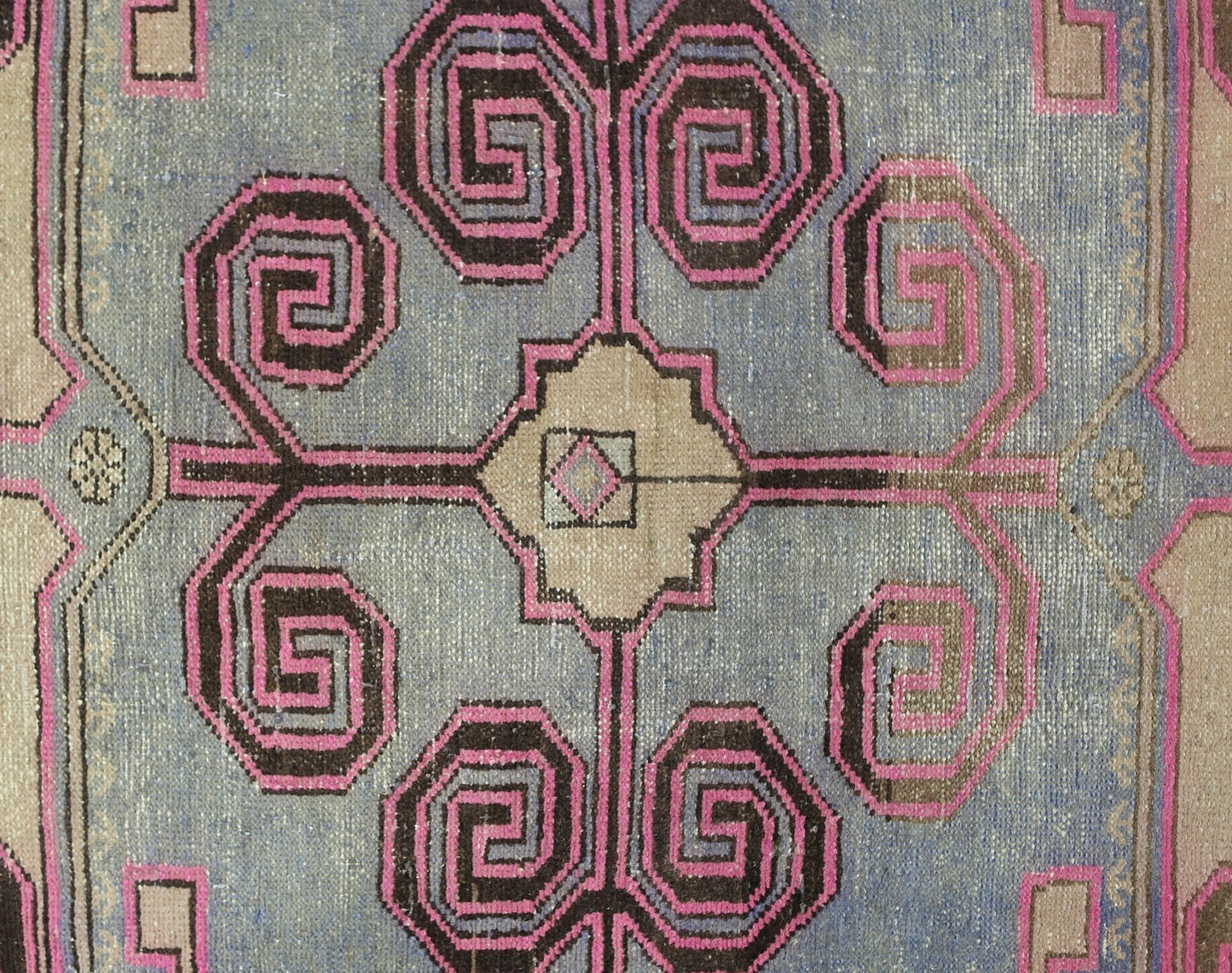 A vintage Persian Hamadan rug featuring a central geometric floral motif in pink and brown.