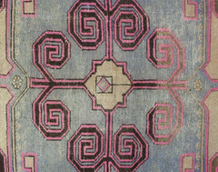 A vintage Persian Hamadan rug featuring a central geometric floral motif in pink and brown.