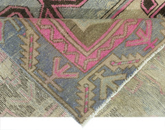 A folded vintage Persian Hamadan rug featuring geometric patterns in pink, blue, and beige tones.