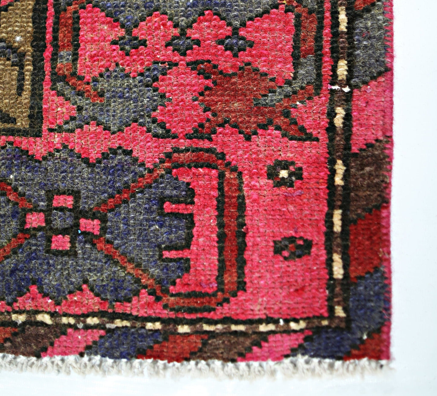 A close-up of a vintage Persian Hamadan rug featuring geometric floral patterns in red and blue.