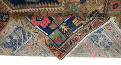 A vintage Persian Hamadan rug with a folded corner revealing its intricate geometric wool pattern.