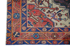 A corner view of a vintage Persian rug featuring intricate floral patterns in red, blue, and cream.
