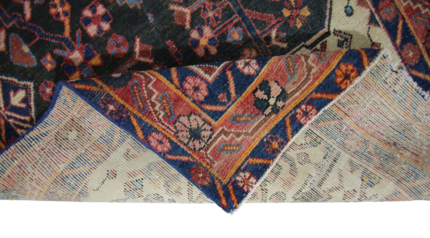 A corner of a vintage Persian rug folded over to show its intricate floral pattern and wool weave.