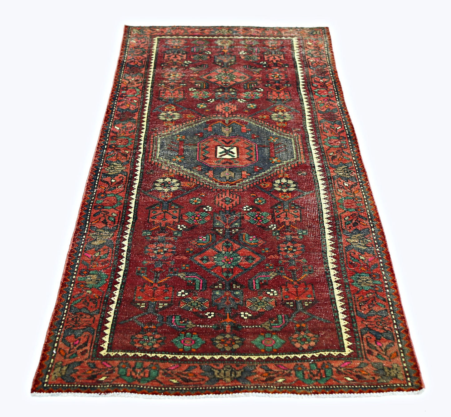 A rectangular vintage Persian rug featuring a red field with intricate geometric floral patterns.