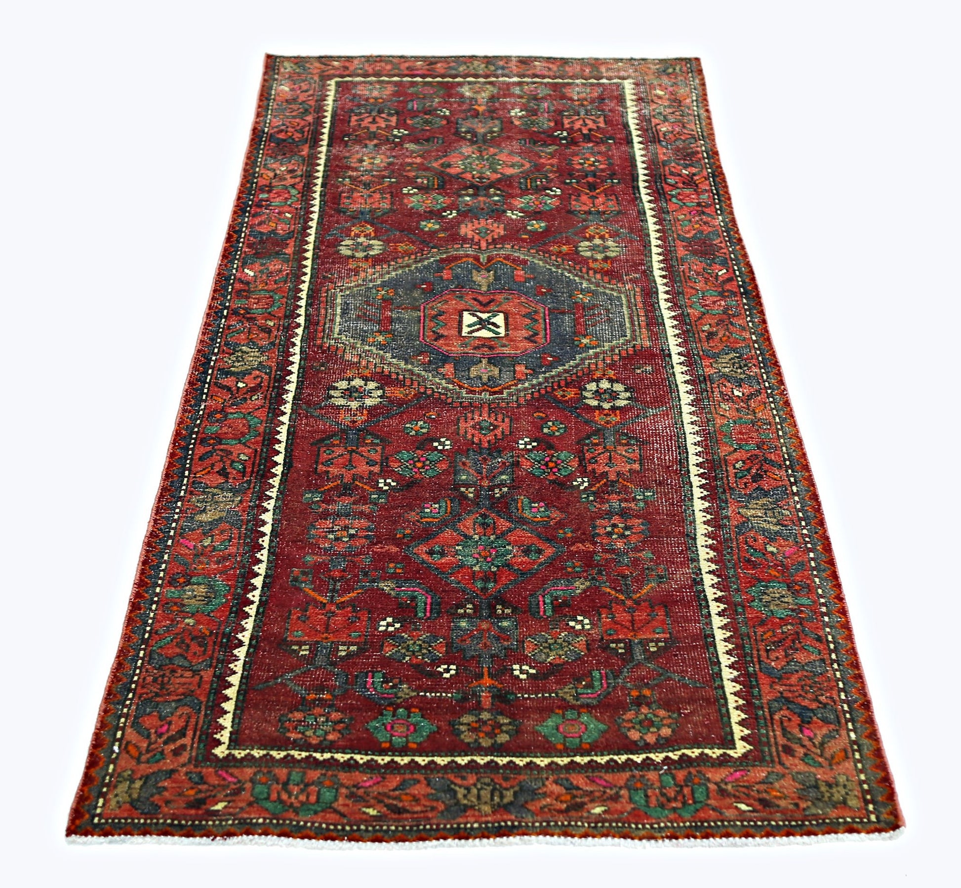 A rectangular vintage Persian rug featuring a red field with intricate geometric floral patterns.