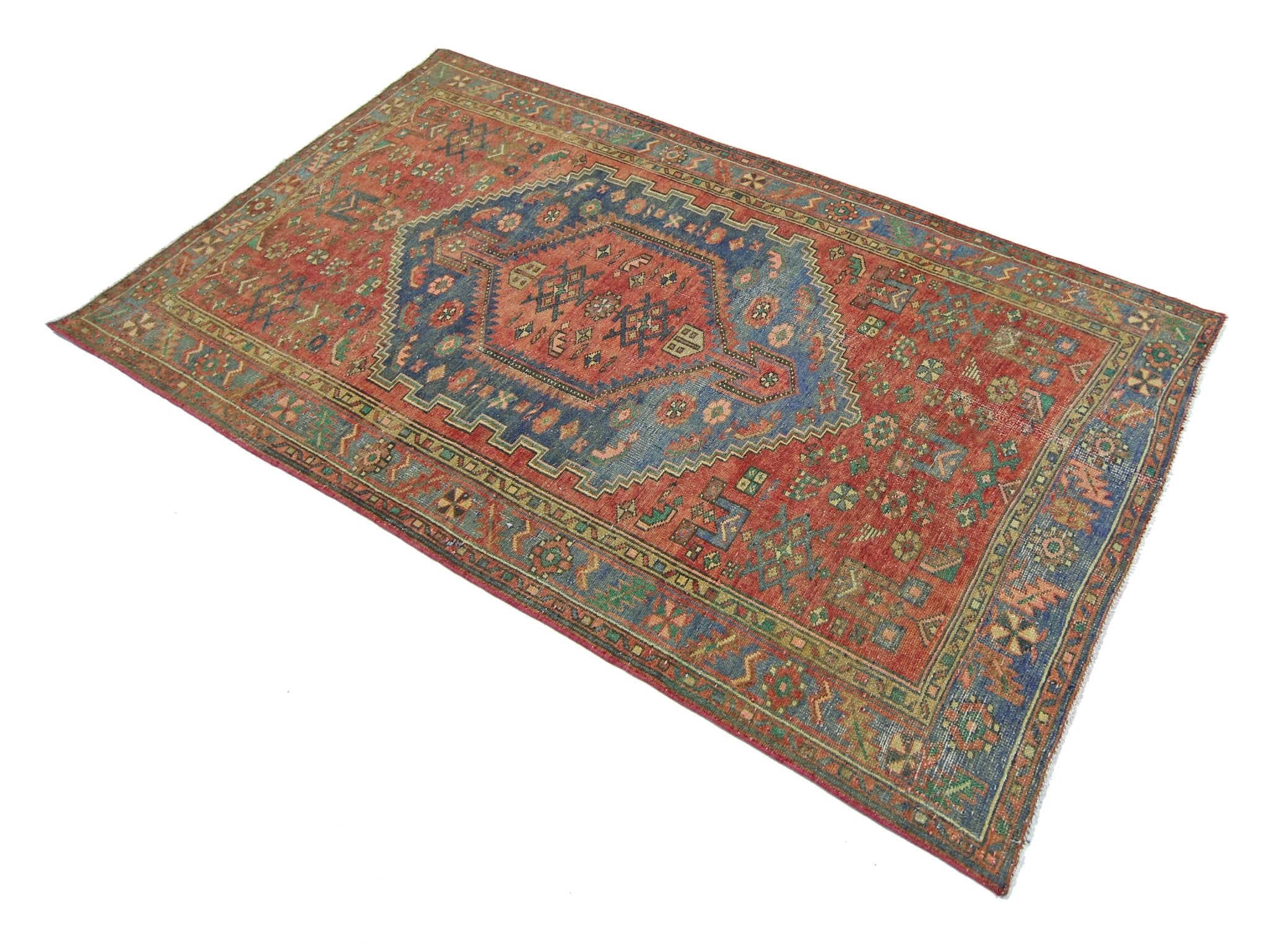 A vintage handmade Persian Hamadan rug featuring a geometric blue medallion on a red field.