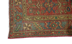 A corner view of a vintage Persian Hamadan rug featuring intricate geometric patterns in red and blue.