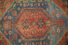 A vintage Persian Hamadan rug featuring a central red medallion with geometric patterns on blue.