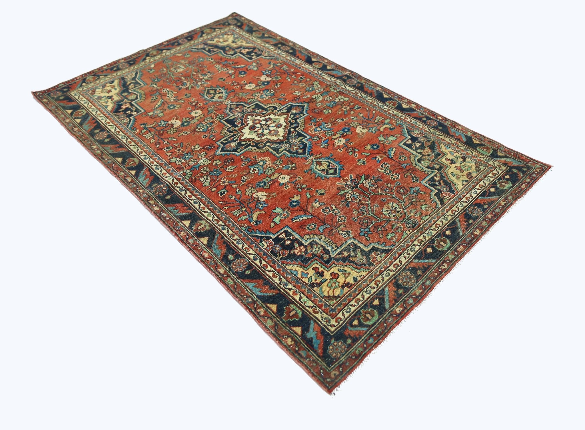 A vintage handmade Persian rug featuring a central medallion on a red field with floral patterns.