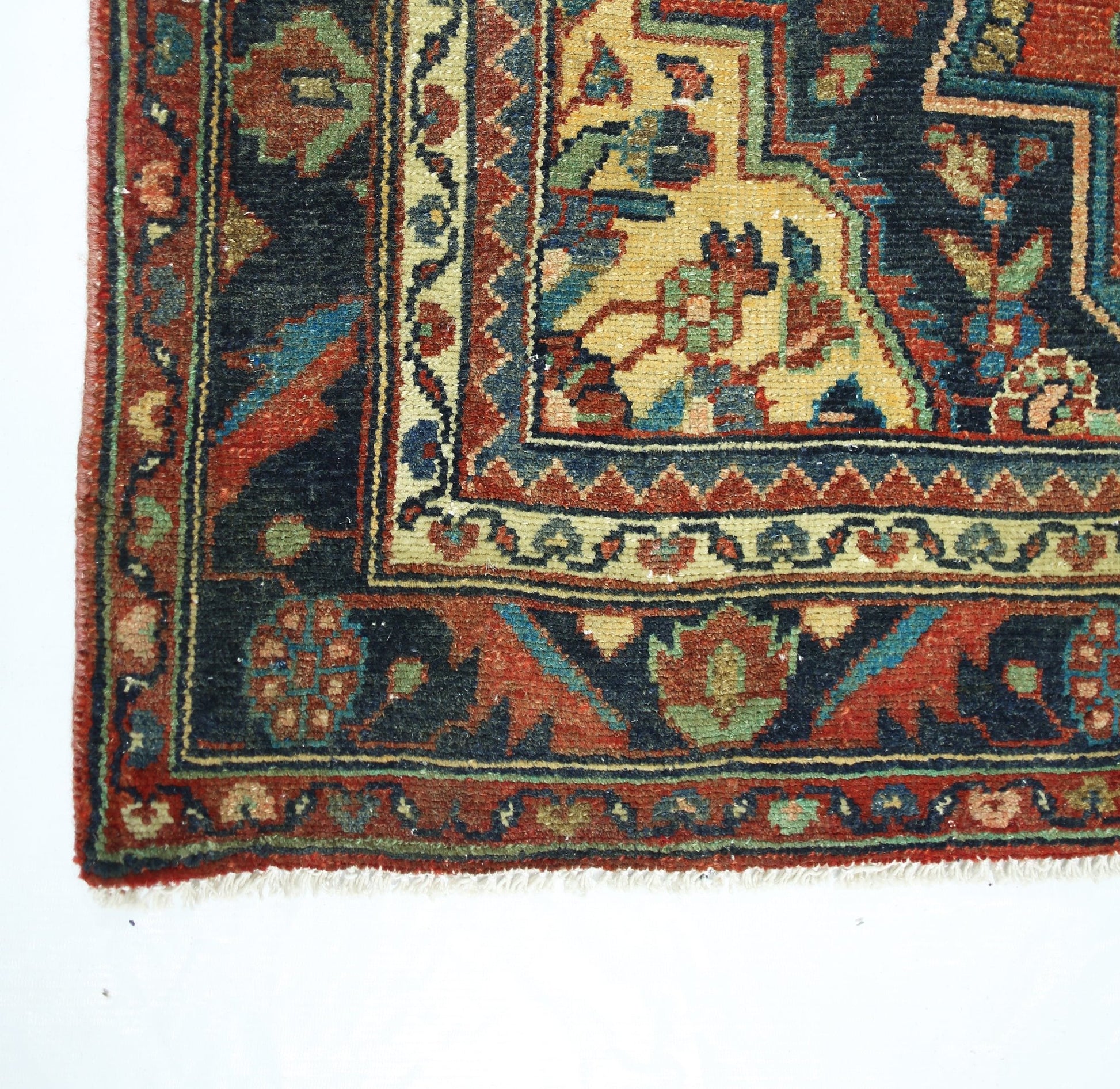 A corner view of a vintage Persian rug featuring intricate floral patterns in red, blue, and gold.