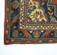 A corner view of a vintage Persian rug featuring intricate floral patterns in red, blue, and gold.