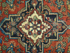 A vintage Persian rug featuring a central cream medallion with floral motifs on a dark blue field.