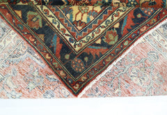 A corner of a vintage Persian rug is folded back to reveal its intricate floral pattern and weave.