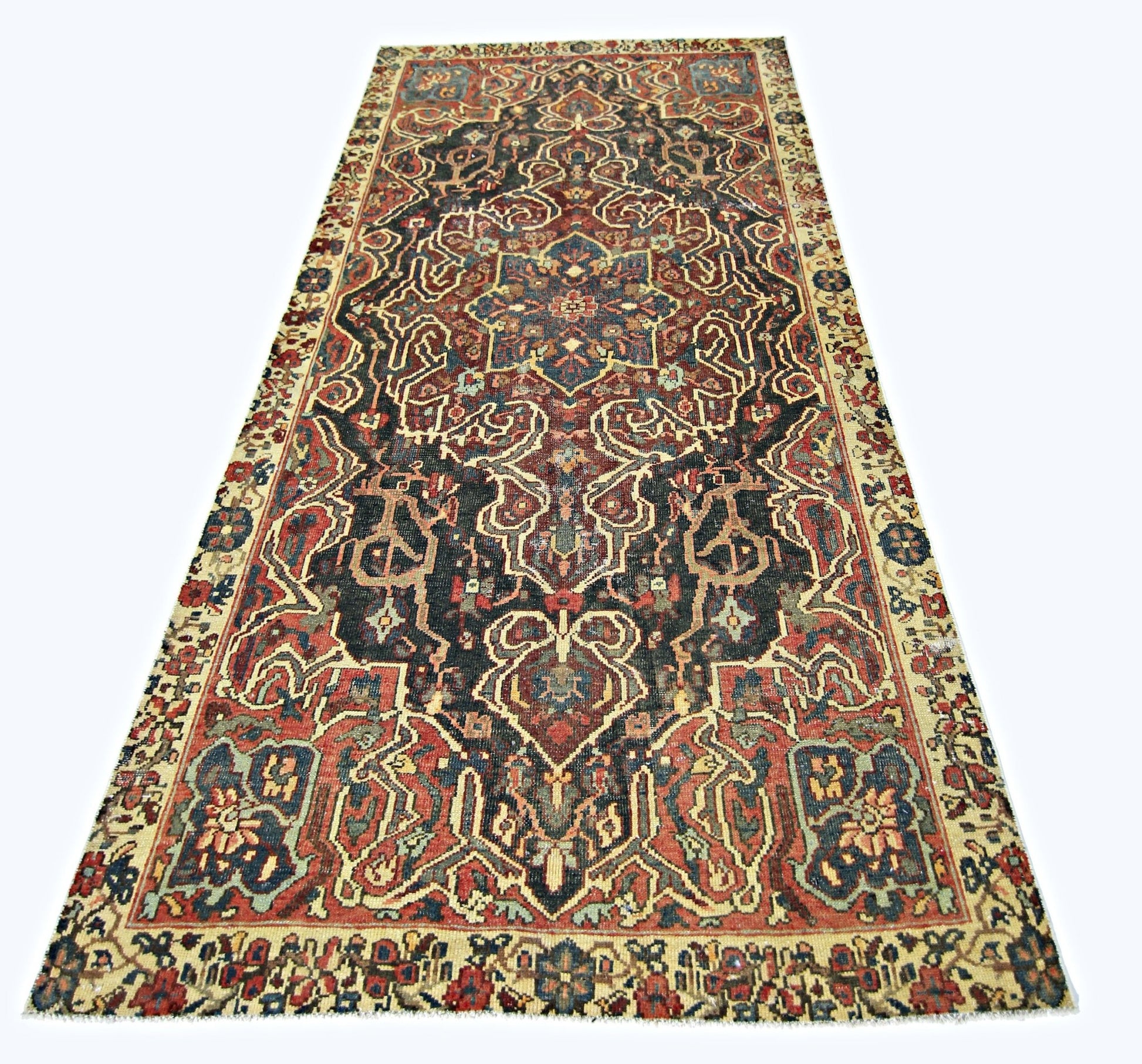 A vintage handmade Persian rug featuring a dark central medallion and intricate floral patterns.