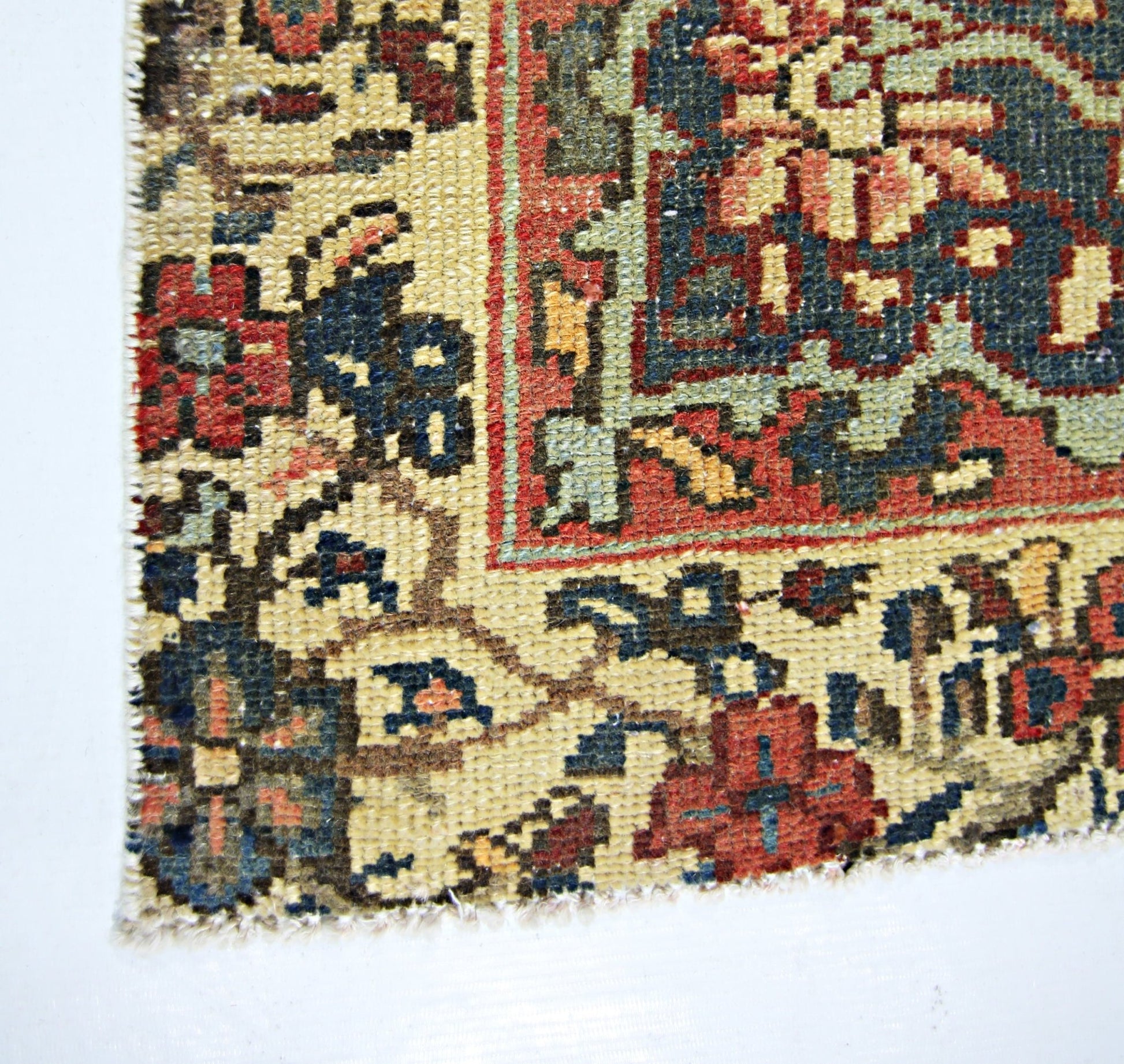 A close-up of a vintage Persian rug featuring intricate floral patterns in red, blue, and cream.