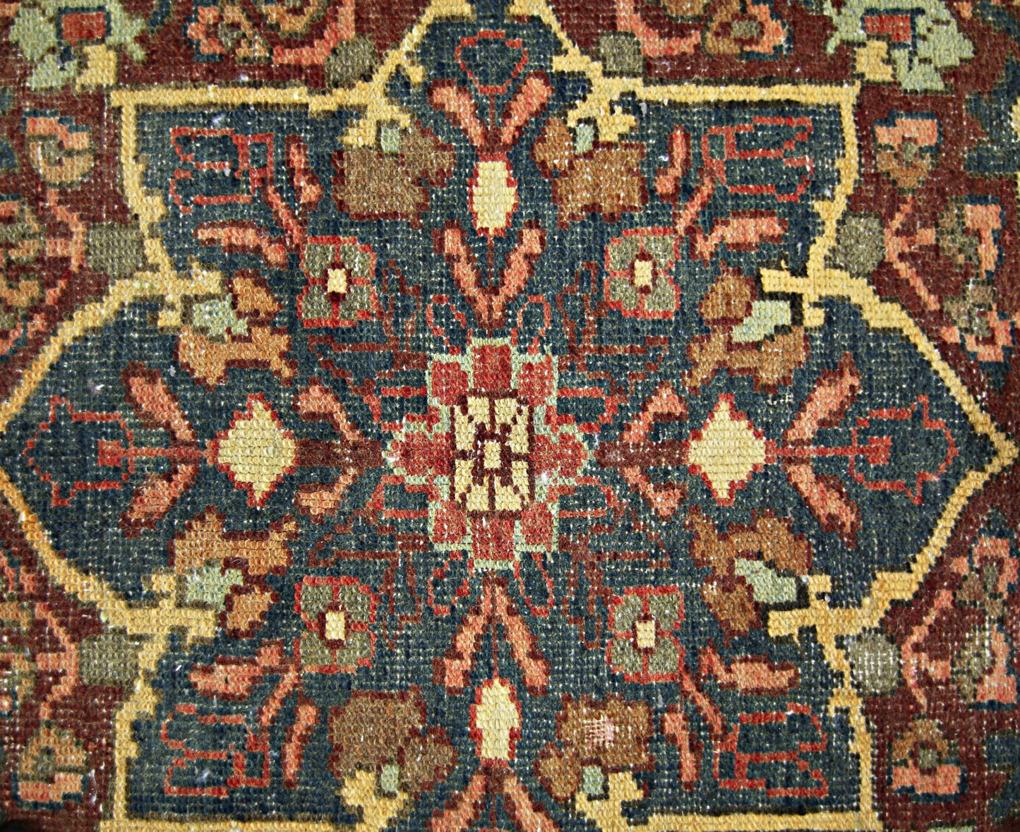 A vintage Persian rug featuring a detailed geometric floral medallion in blue, red, and tan tones.