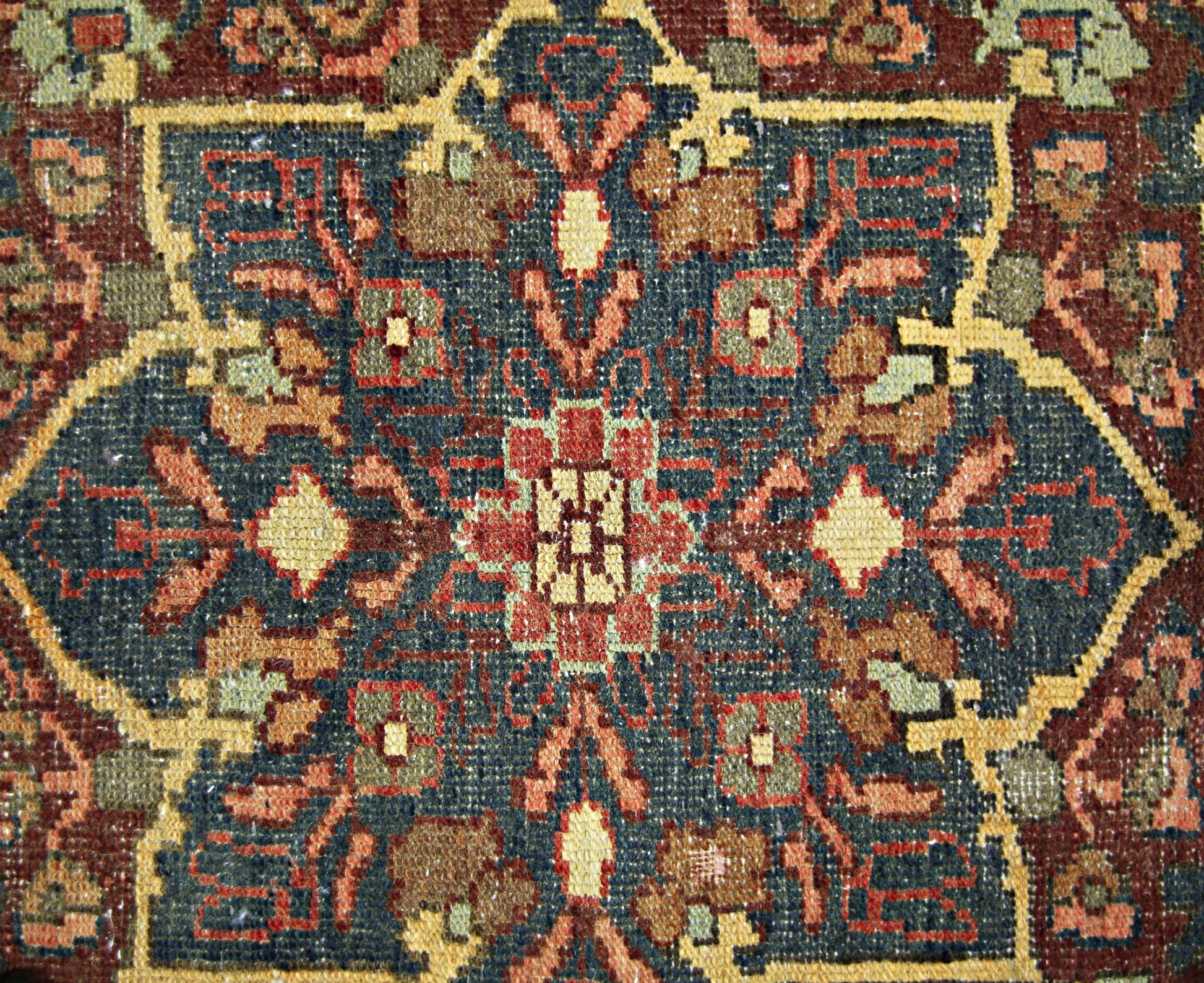 A vintage Persian rug featuring a detailed geometric floral medallion in blue, red, and tan tones.