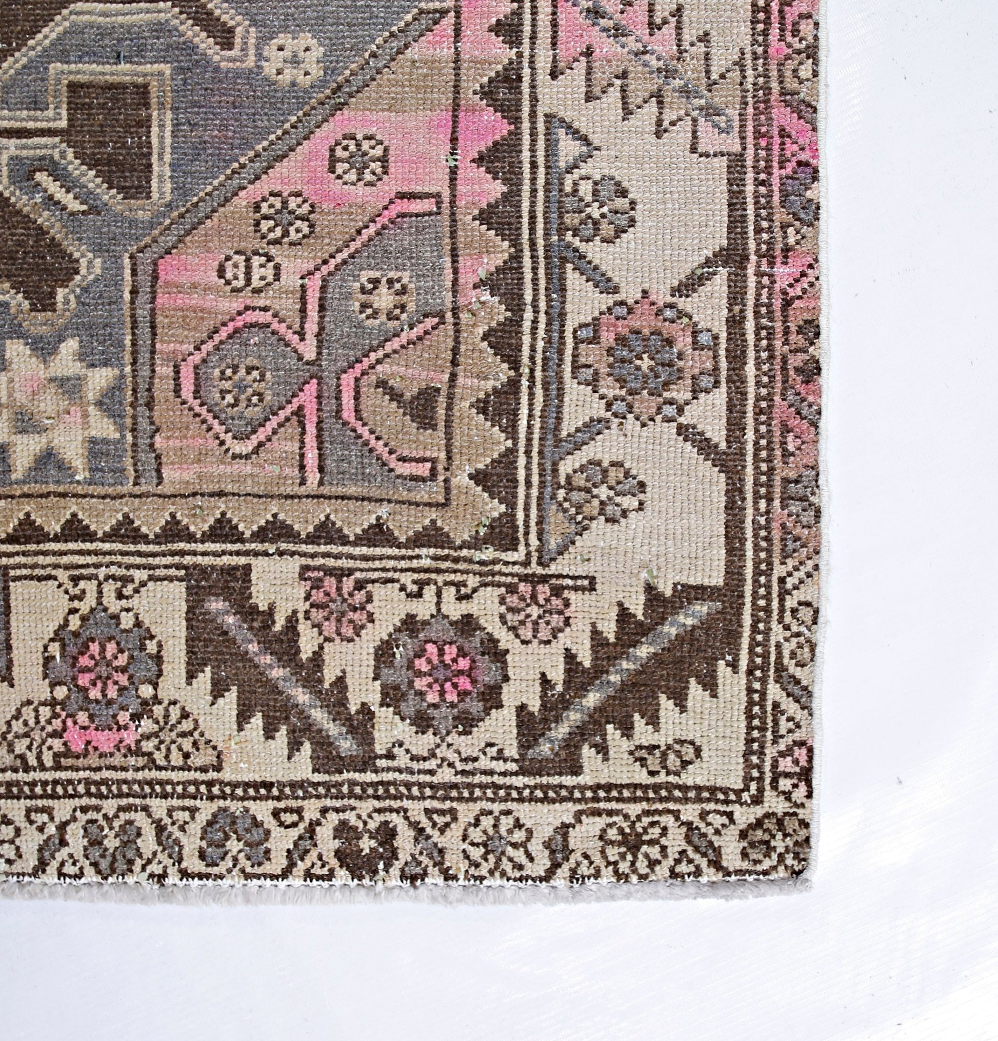 A vintage Persian Hamadan rug featuring geometric floral patterns in shades of pink, grey, and tan.