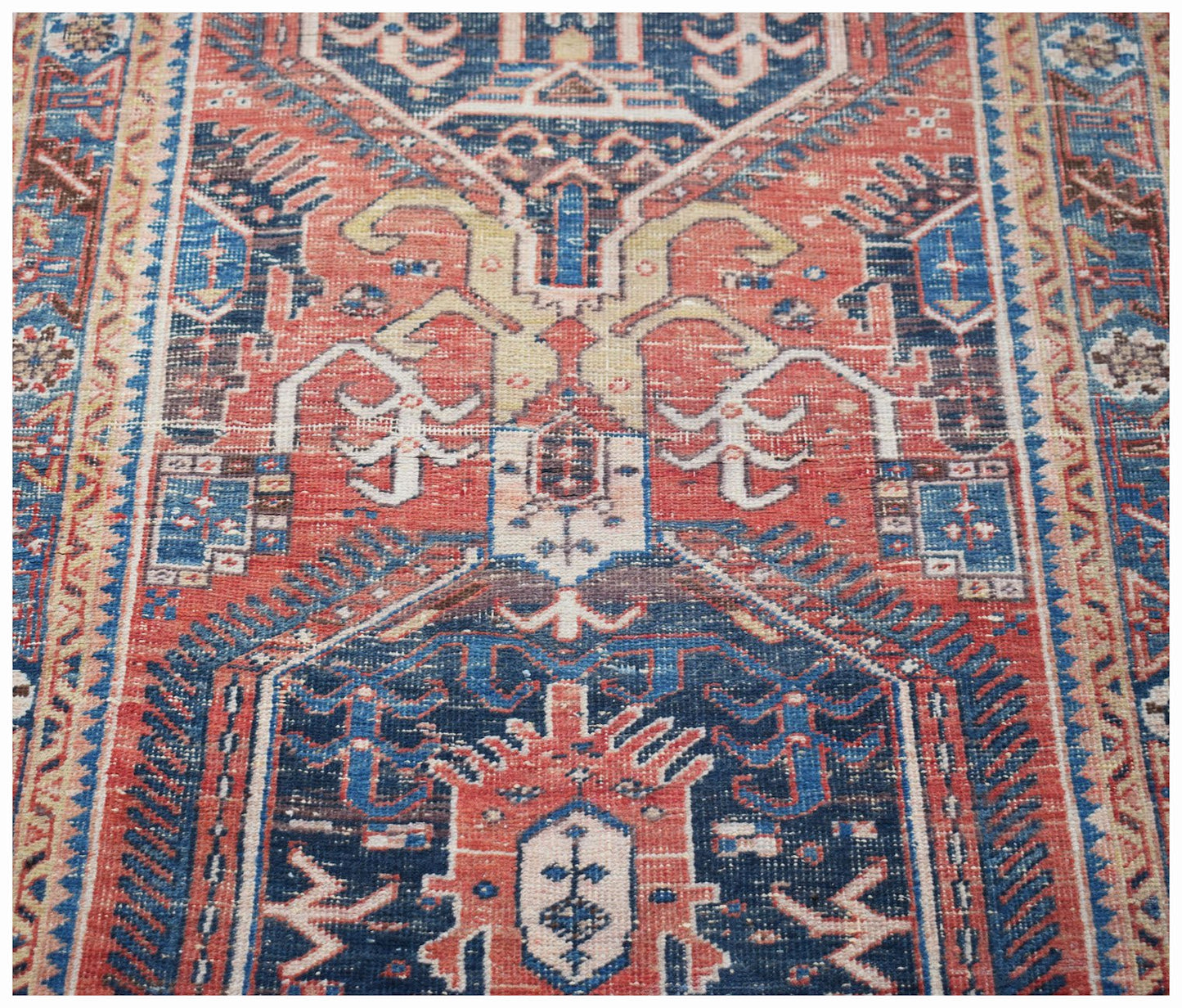 A vintage handwoven Persian Hamadan rug featuring a geometric pattern in red, blue, and cream.