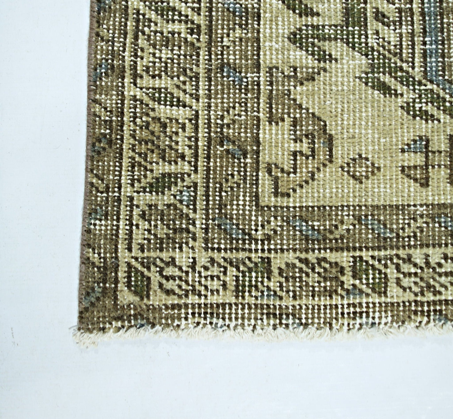 A corner view of a vintage Persian Hamadan rug featuring intricate geometric patterns in olive and cream.