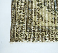 A corner view of a vintage Persian Hamadan rug featuring intricate geometric patterns in olive and cream.