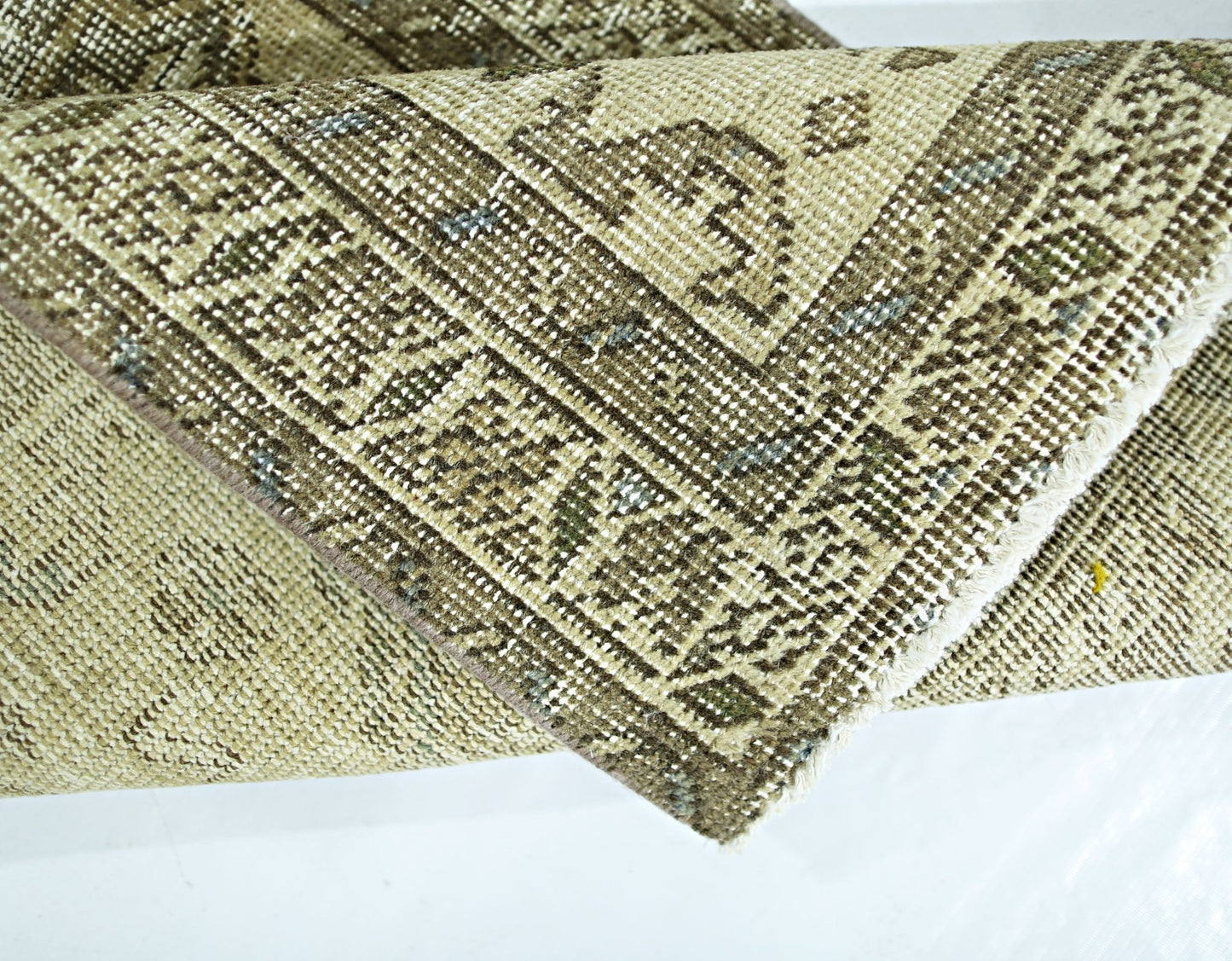 A folded vintage Persian Hamadan rug featuring intricate geometric patterns in neutral tones.
