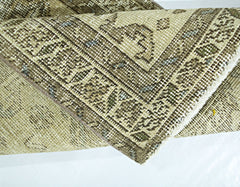A folded vintage Persian Hamadan rug featuring intricate geometric patterns in neutral tones.