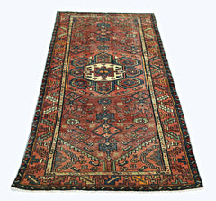 A vintage Persian Hamadan runner featuring a geometric medallion pattern in red, blue, and cream.
