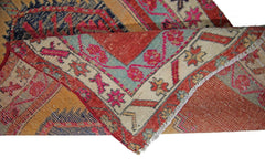 A folded vintage Persian Hamadan runner featuring intricate geometric patterns in red, blue, and gold.