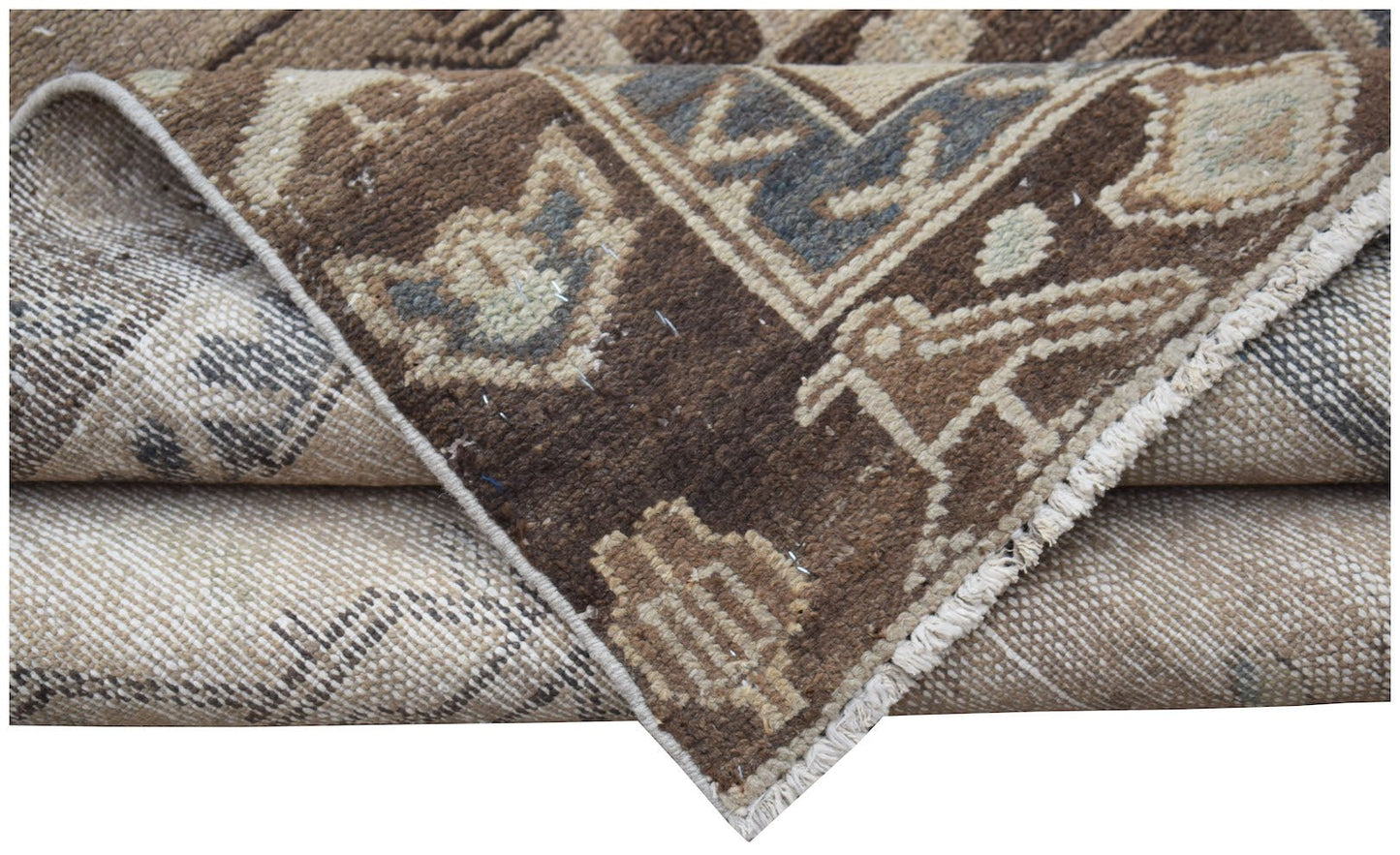 A folded vintage Persian Hamadan runner featuring a brown and beige geometric wool pattern.