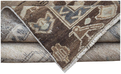 A folded vintage Persian Hamadan runner featuring a brown and beige geometric wool pattern.