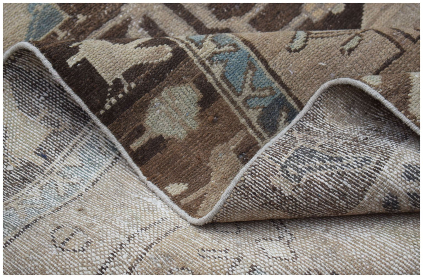 A corner view of a vintage handwoven Persian Hamadan runner with a worn brown and blue pattern.