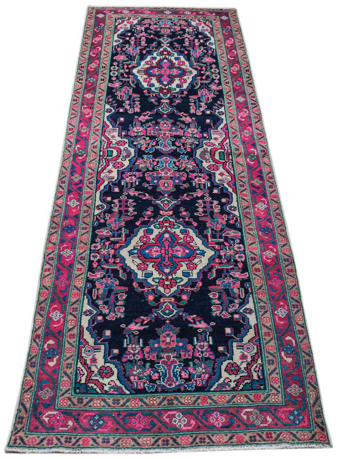 A vintage Persian Hamadan runner featuring a dark blue field with vibrant pink and cream patterns.