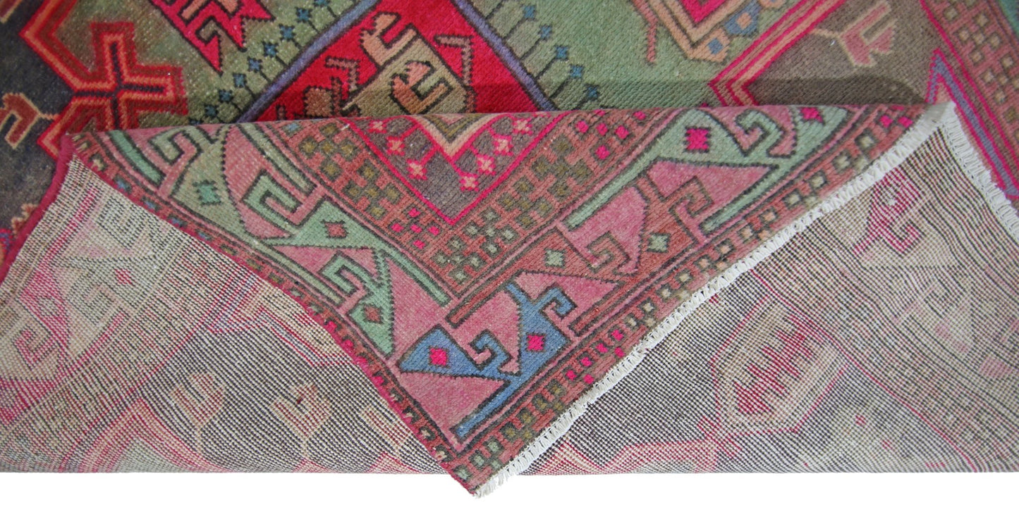 A vintage Persian Hamadan runner featuring a geometric pattern in vibrant pink, green, and blue.