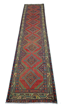 A vintage Persian Hamadan runner rug featuring a red field with repeating diamond medallions.