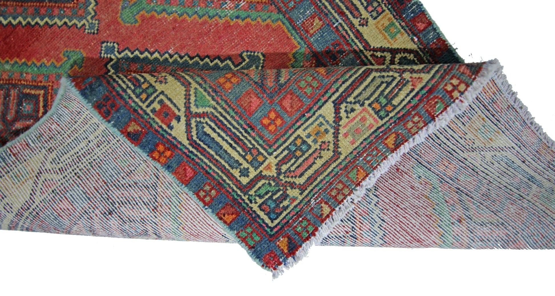 A vintage Persian Hamadan runner with a geometric red and blue pattern folded to show its backing.