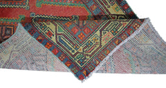 A vintage Persian Hamadan runner with a geometric red and blue pattern folded to show its backing.