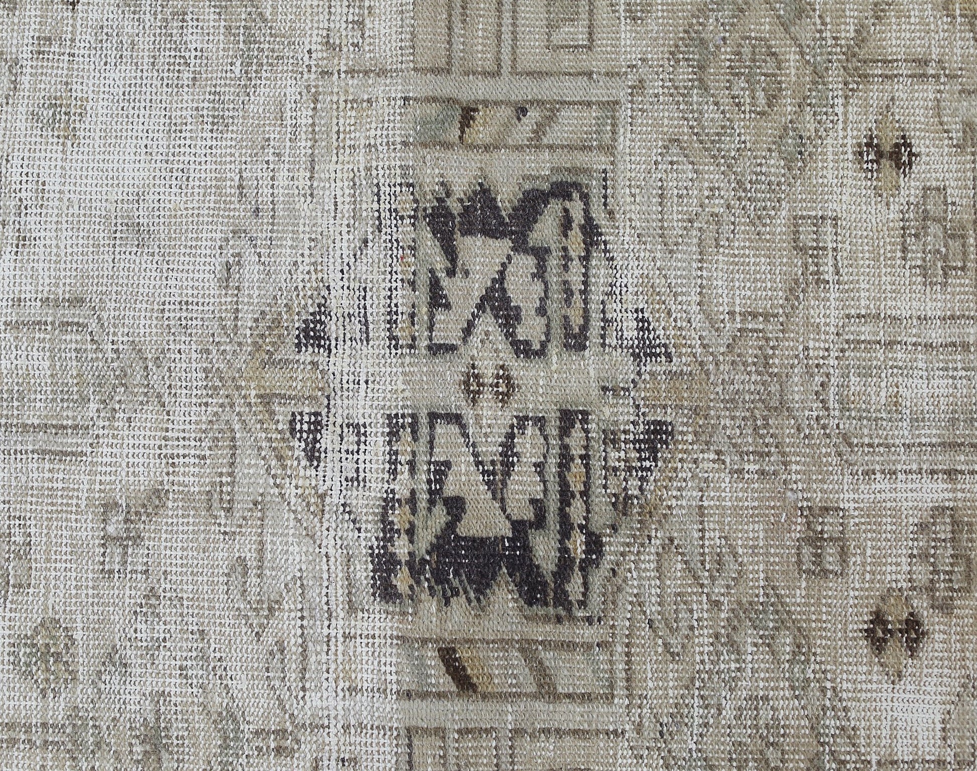 A close-up of a vintage Persian Hamadan runner featuring a faded geometric medallion pattern.
