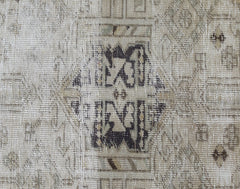 A close-up of a vintage Persian Hamadan runner featuring a faded geometric medallion pattern.