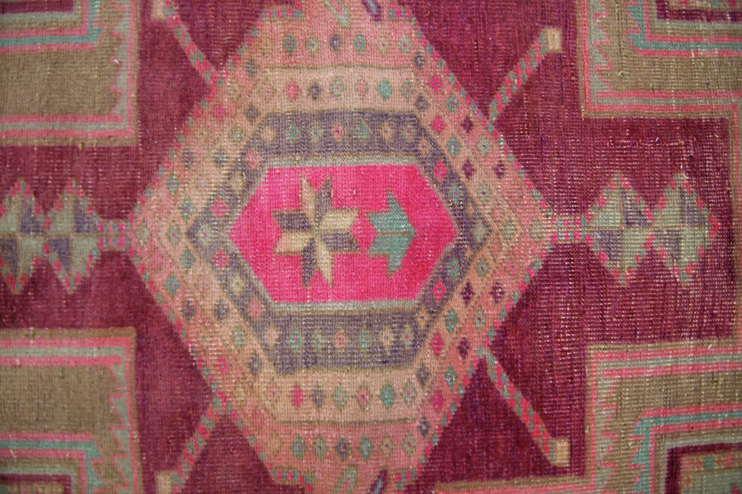 A vintage Persian Hamadan runner featuring a geometric medallion in vibrant pink and earthy tones.