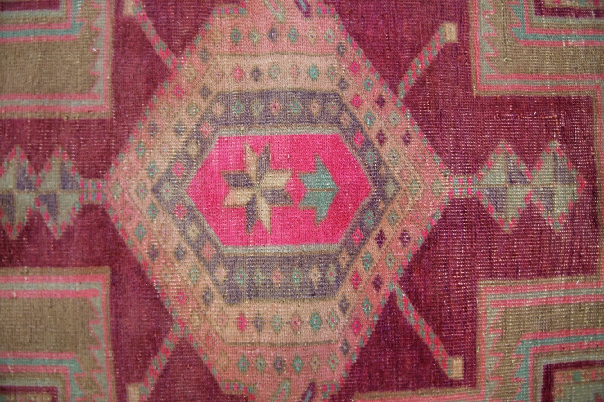 A vintage Persian Hamadan runner featuring a geometric medallion in vibrant pink and earthy tones.