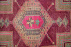 A vintage Persian Hamadan runner featuring a geometric medallion in vibrant pink and earthy tones.