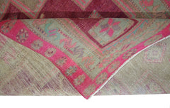 A folded vintage Persian Hamadan runner featuring a vibrant pink border and geometric patterns.