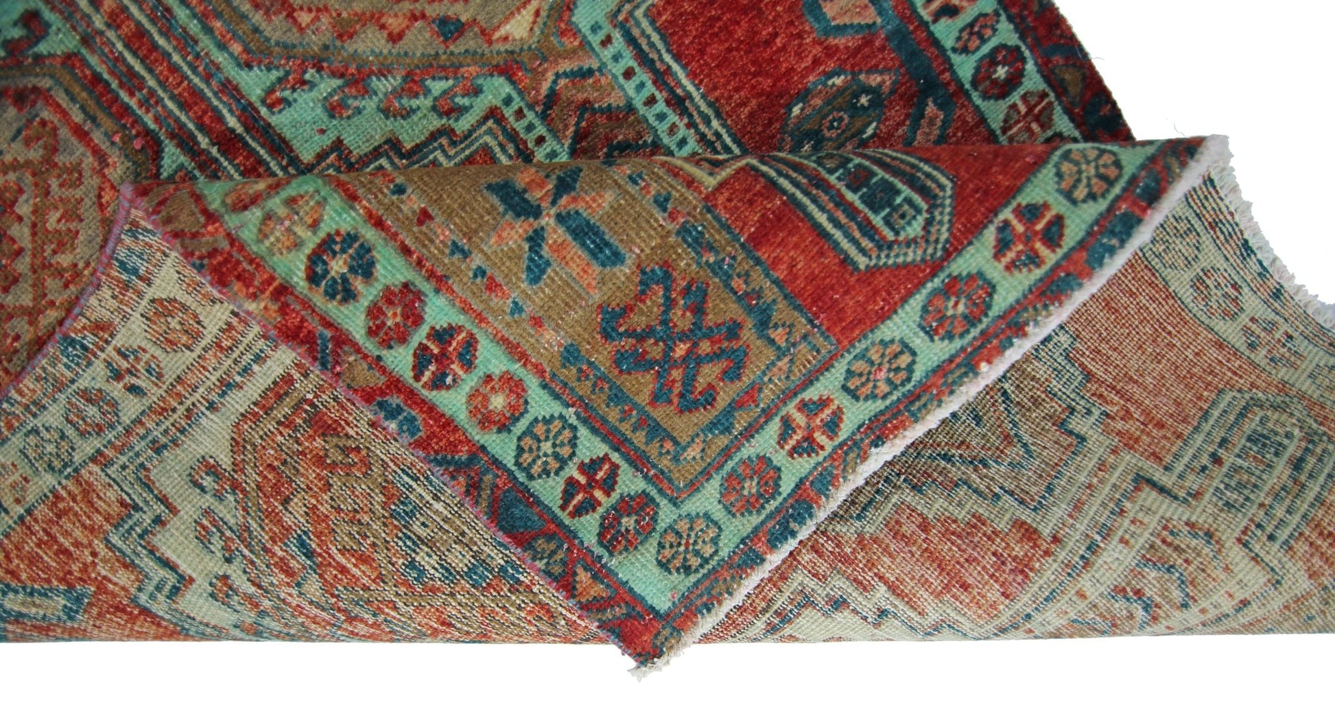 A folded vintage Persian Hamadan runner featuring intricate geometric patterns in red and teal.