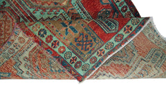 A folded vintage Persian Hamadan runner featuring intricate geometric patterns in red and teal.