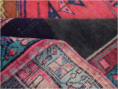 A folded vintage Persian Hamadan runner featuring intricate geometric patterns in pink and blue.