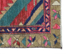 A close-up of a vintage Persian Hamadan runner featuring geometric patterns in red, blue, and green.